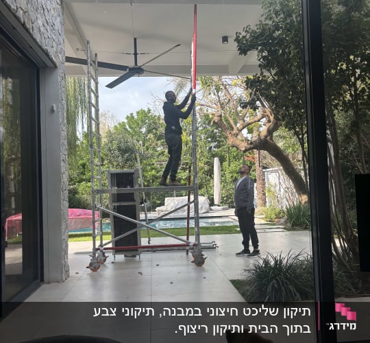 אדם על סולם מתקין מאוורר תקרה בחוץ